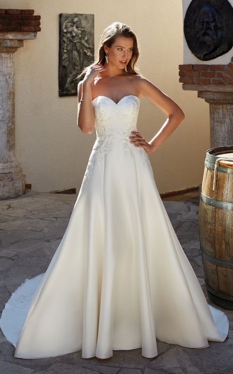 Eddy k Mikado wedding gown with sweetheart neckline on blonde woman in courtyard.