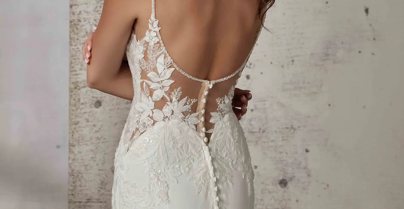 Back of Eddy K crepe wedding dress with spaghetti straps and unlined skin back on bridal model standing in studio