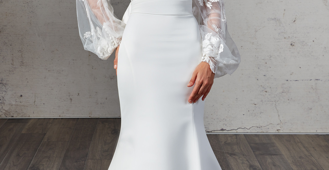 Eddy K mermaid wedding dress with detached lace sleeves and straight neckline on woman with a pony tail.
