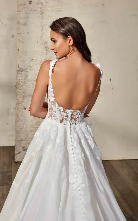 Back close up of Eddy K organza and lace wedding dress with unlined back and lace straps on bridal model photographed in a studio.