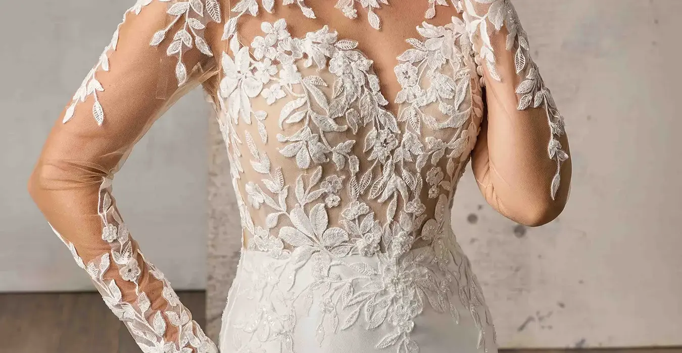 Close up of Eddy K Mikado mermaid wedding dress with a high neck neckline and a long sleeves body on a bridal model posing in a studio.