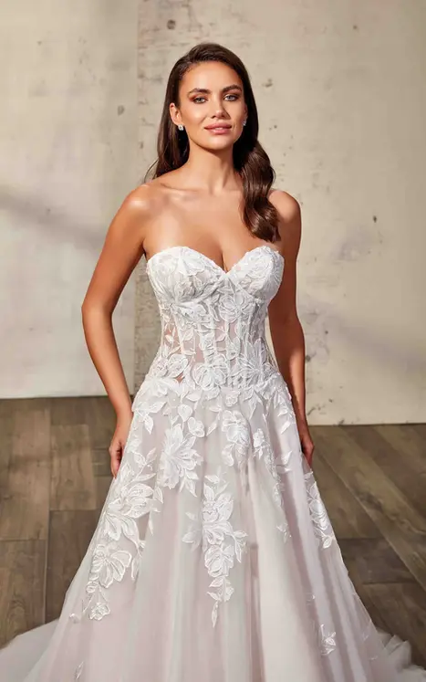 close up of bride wearing wedding ballgown by wedding dress designer Eddy K with ivory lace and minimal beading over ivory tulle, lavender tulle & matte lining, unlined skin bodice, lavender buttons to end of train and drop waist. She is photograph in a beautiful modern studio.