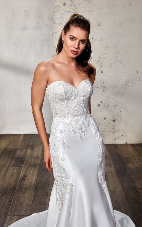 woman wearing mermaid sweetheart wedding gown with beaded ivory lace and sequins over ivory tulle with Mikado skirt and buttons to end of train. 