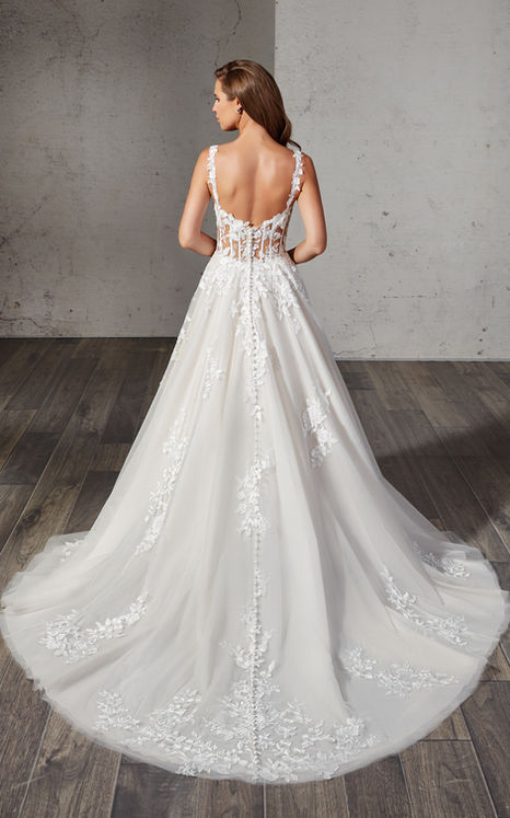 Back of Eddy K A-line wedding gown with spaghetti straps and champagne tulle on longhaired woman.
