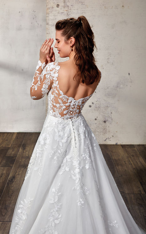 woman wearing Eddy K bridal A-Line long sleeve wedding gown with ivory lace and sequins over tulle with open back