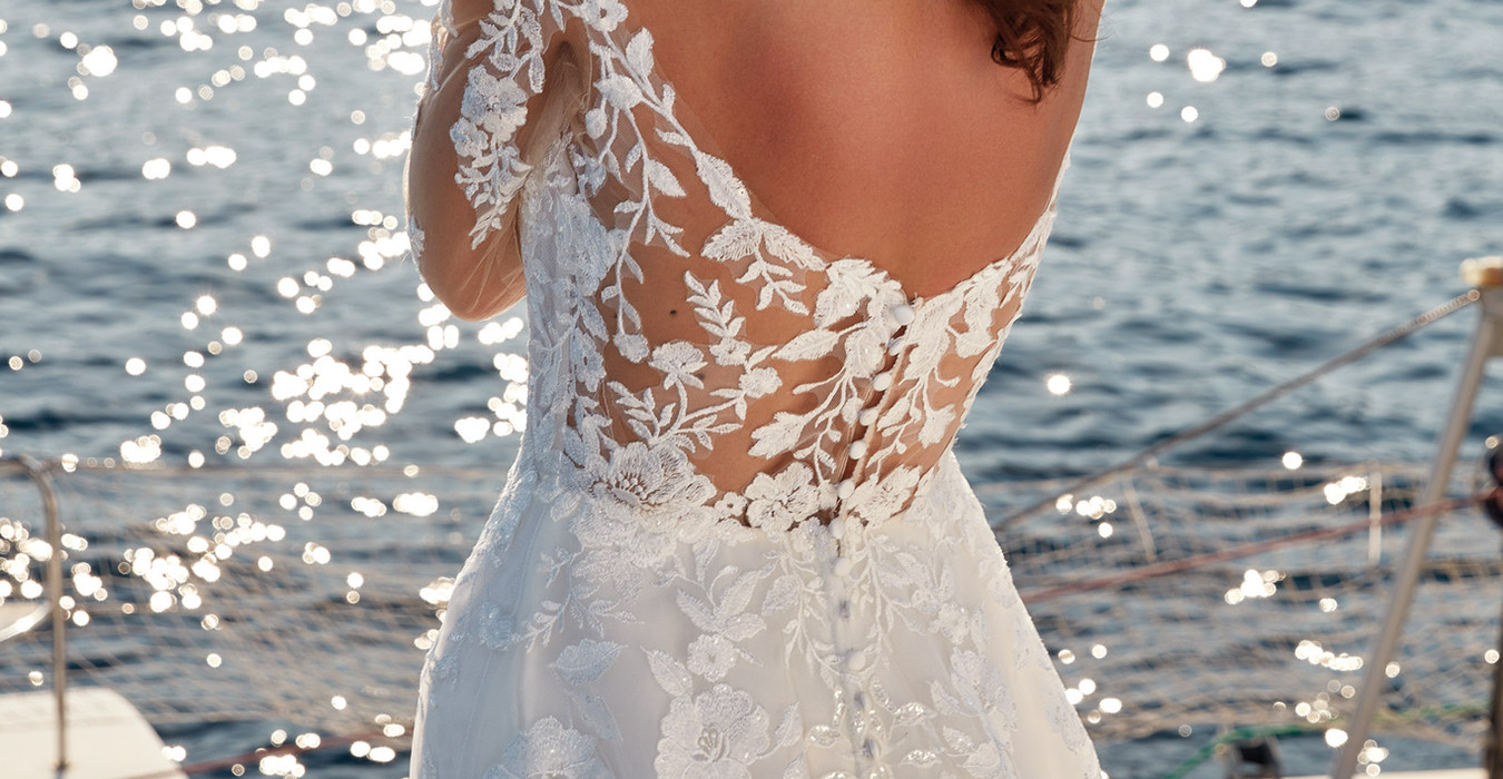woman wearing Eddy K bridal A-Line long sleeve wedding gown with ivory lace and sequins over tulle with open back