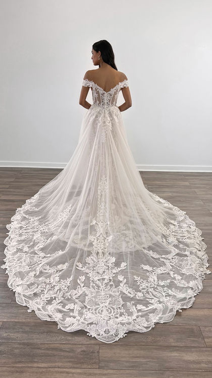 Backview of woman wearing Eddy K mermaid wedding gown with ivory lace and sequins and matching detachable train in studio