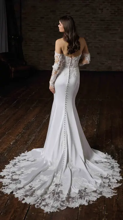 Back of Eddy K fit-n-flare wedding dress with a straight neckline and a strapless body on a bridal model posing in a studio.