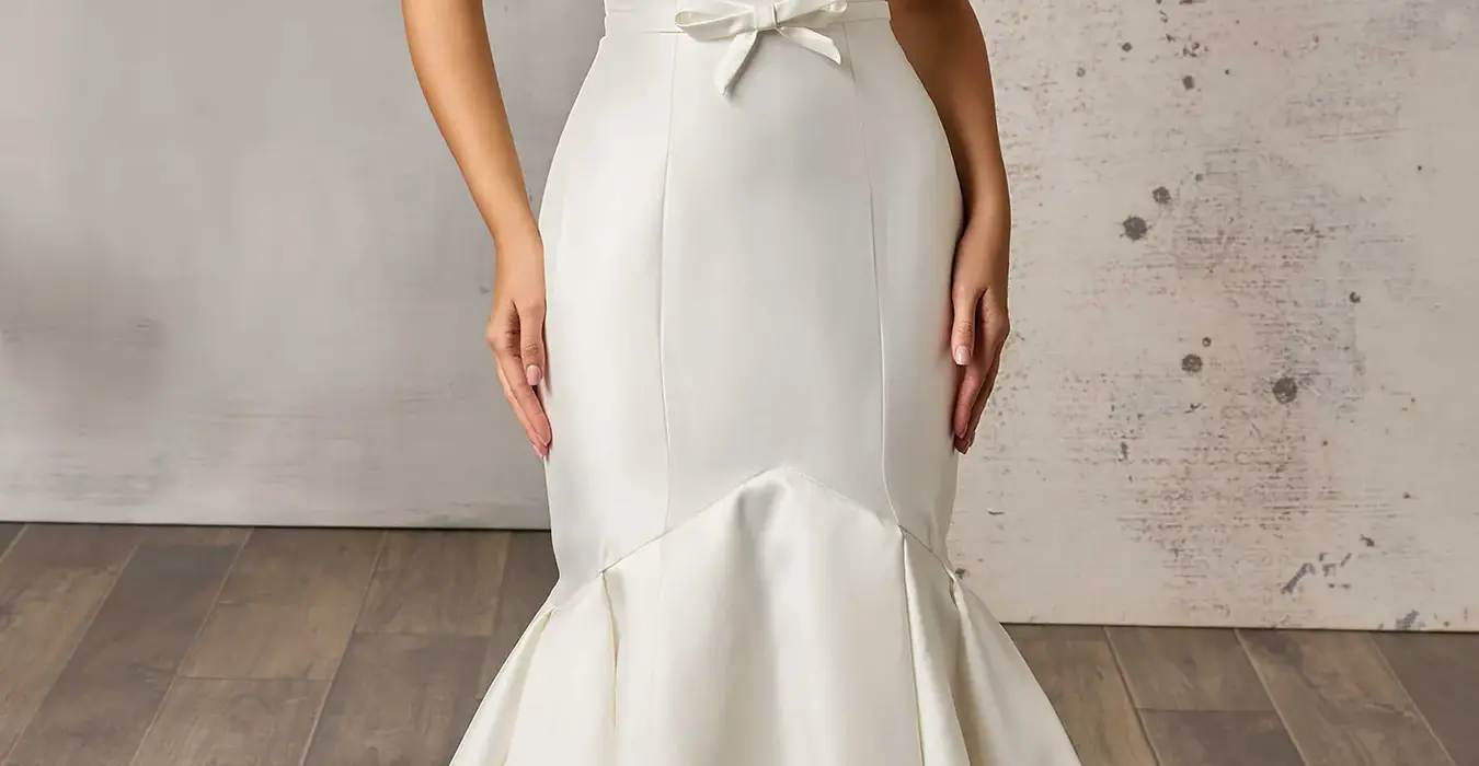 Eddy K mikado mermaid wedding dress with a sweetheart neckline and a strapless body on a bridal model posing in a bridal studio.