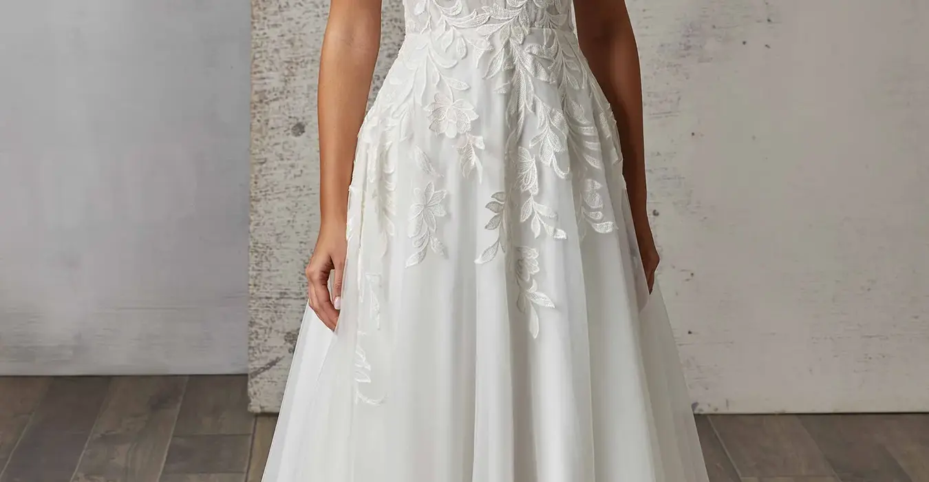 Eddy K A-Line wedding gown with ivory lace over ivory tulle, Chantilly lace unlined bodice on bridal model standing in studio.
