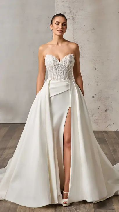 Eddy K mikado fit-n-flare wedding dress with a sweetheart neckline and a strapless body on a bridal model standing in a bridal studio