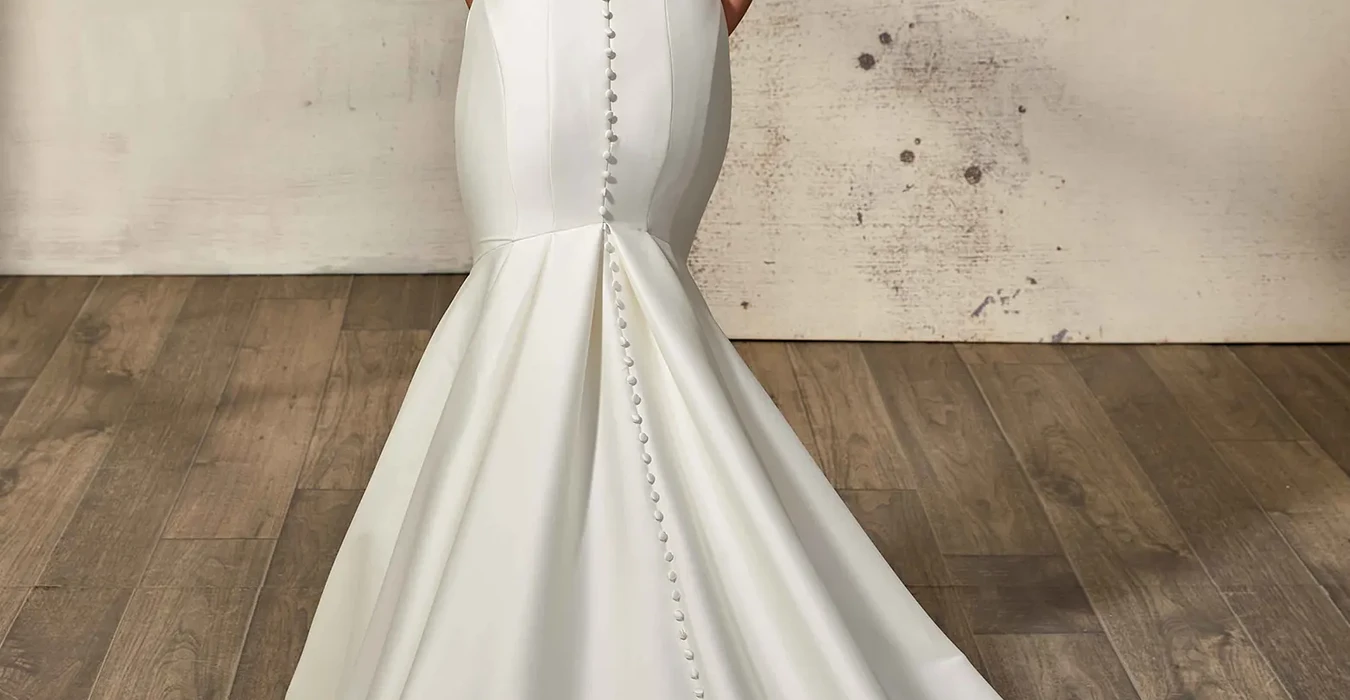 Back of Eddy K strapless mikado mermaid wedding gown with illusion cut-outs in the back on bridal model photographed in a studio.