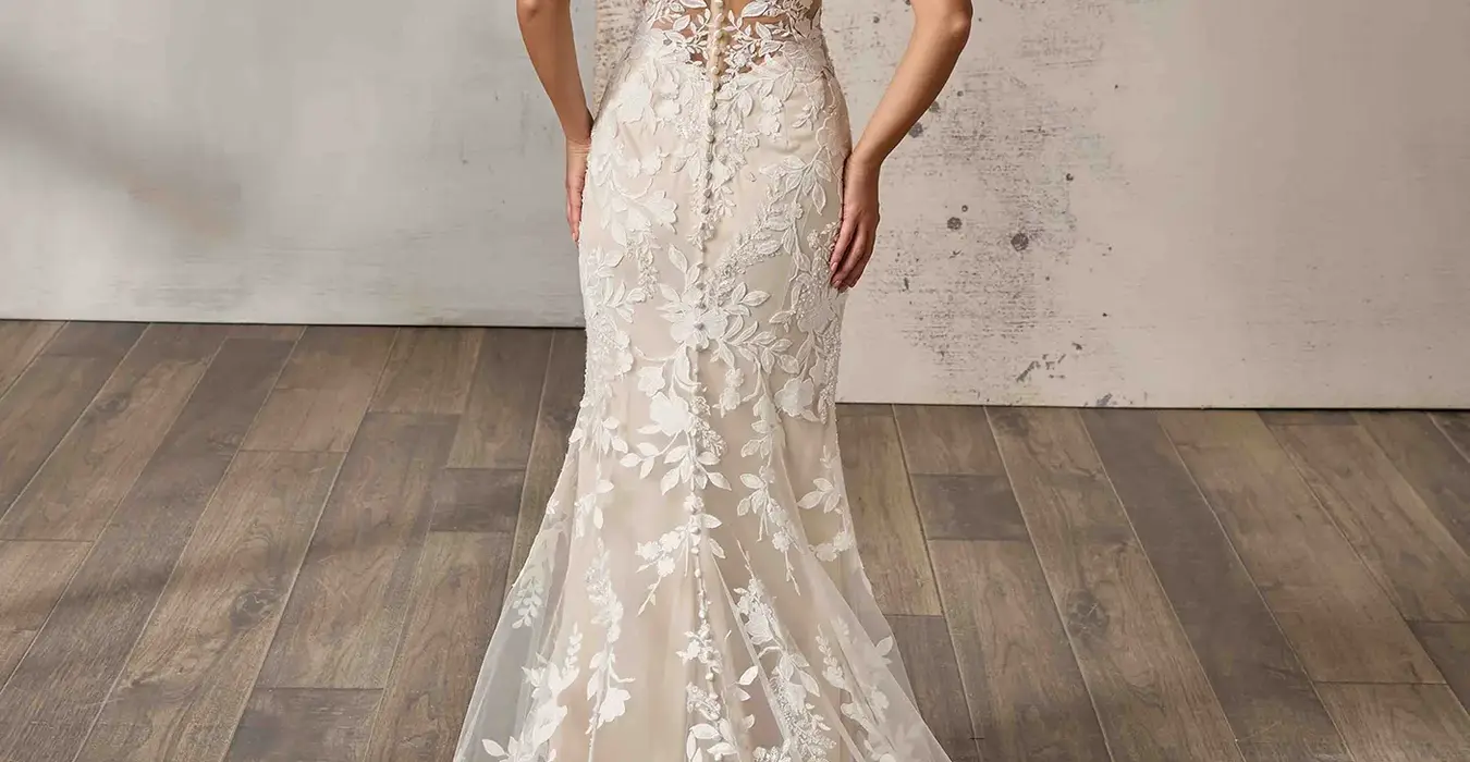 Back of Eddy K lace and tulle fit-n-flare wedding dress with a v-neck neckline and a sleeveless body on a bridal model standing in a bridal studio.