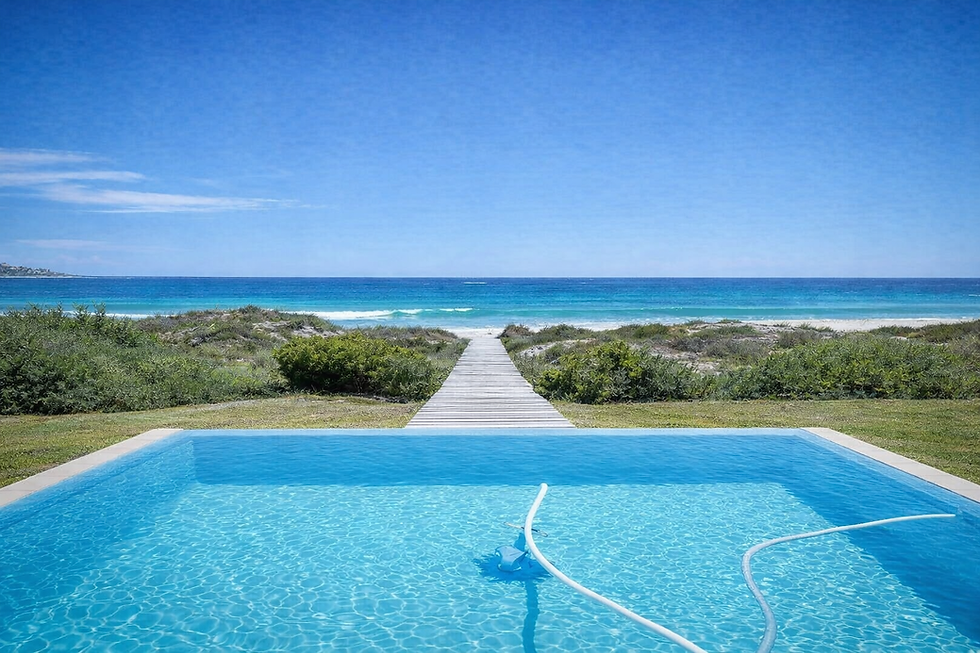 Swimming pool with a path leading to a sandy beach and ocean.