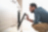 Side view portrait of handsome gentleman in denim shirt looking into oven while squatting