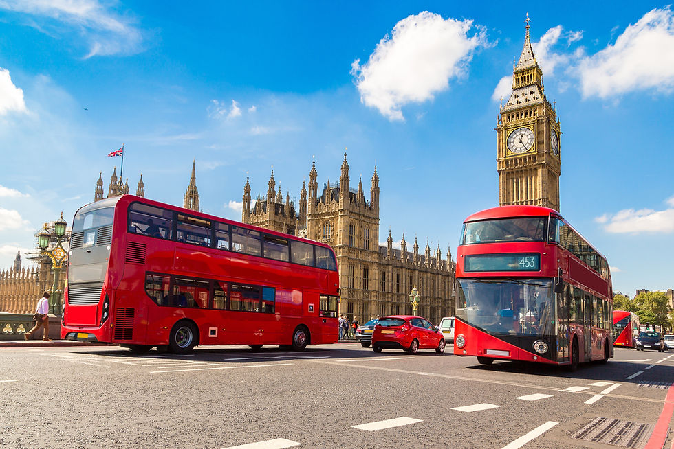Westminster Palace towers over the streets of London with two red buses passing by.