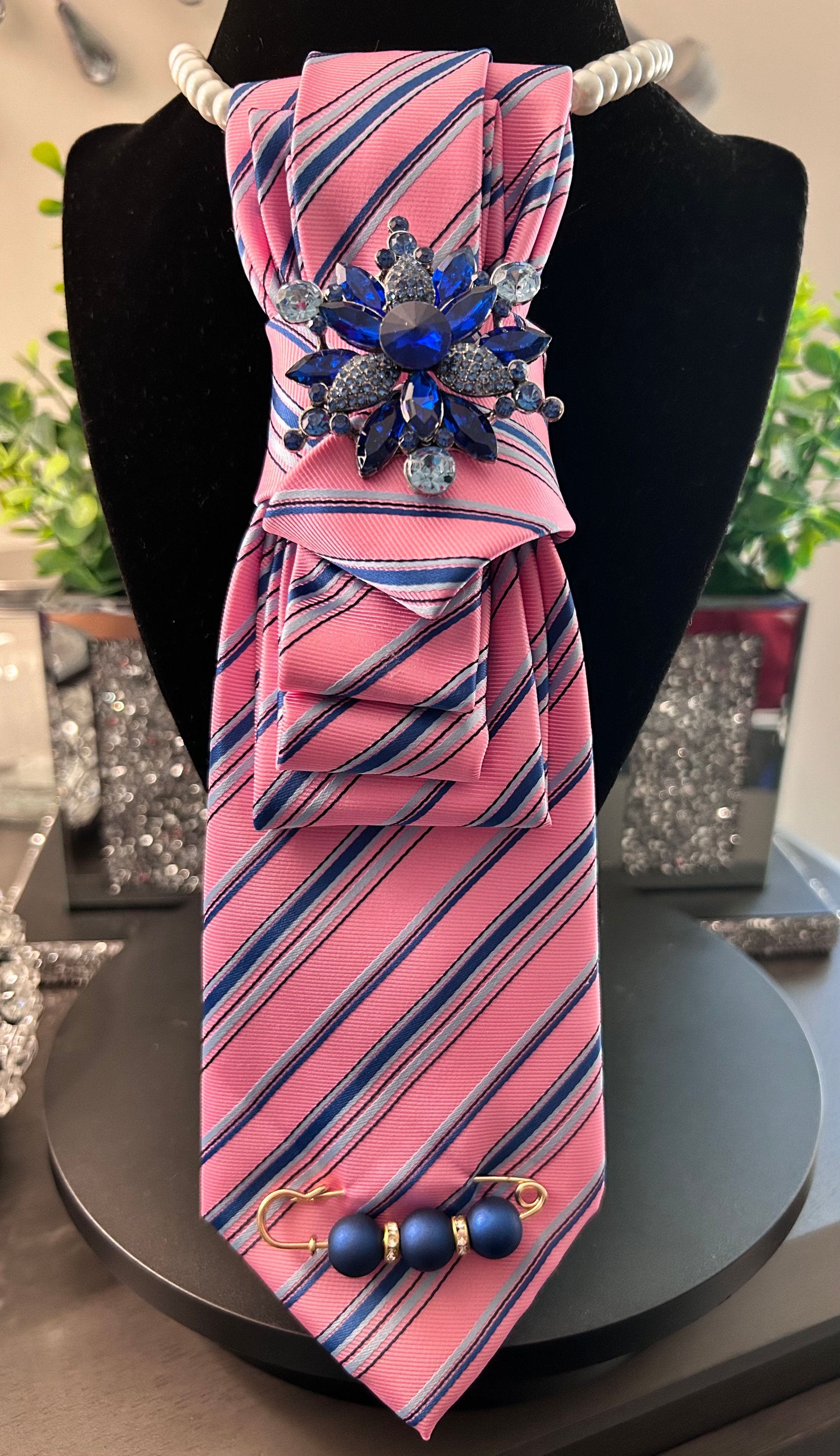 Pink striped tie with bold blue jeweled floral brooch