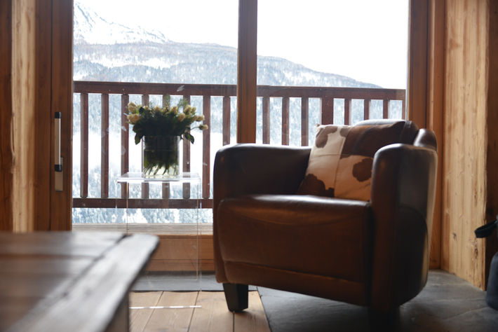 Chalet Rosiere comfortable armchair next to fireplace with snowy mountains in the background 