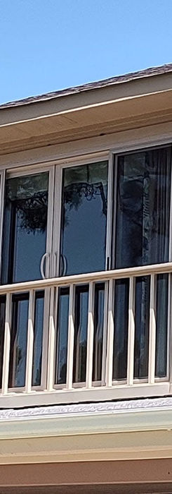 Second-story balcony with sliding glass door and windows.
