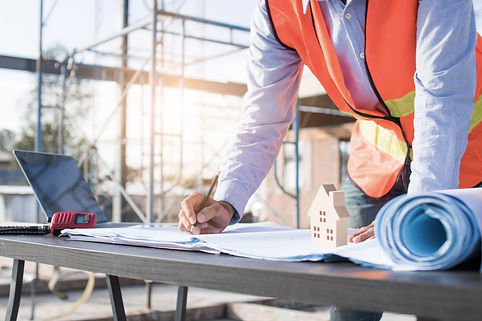 Builder reviewing blueprints for professional glass installation project at construction site.