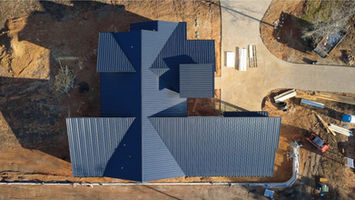 Top-down aerial view of a completed standing seam metal roof on a new construction home in East Texas