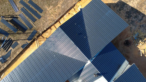 Close-up aerial view of standing seam metal roof panels and valley detail on a new construction home in East Texas