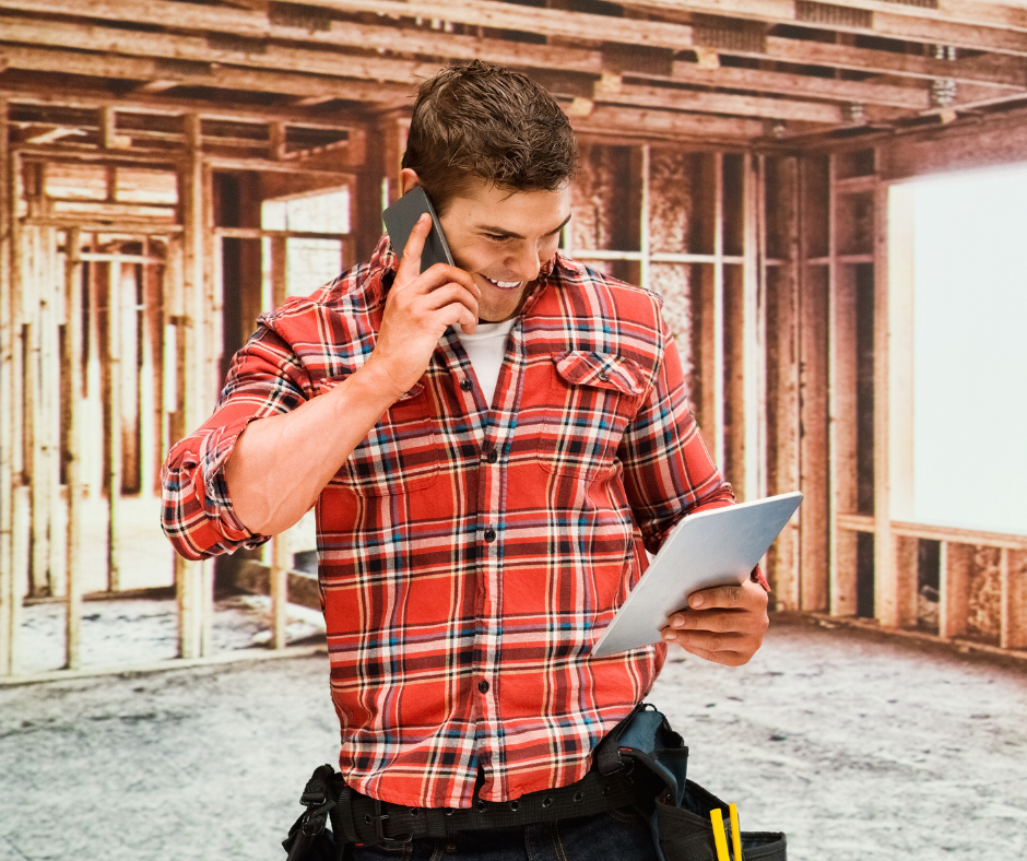 Busy tradesman smiling while taking calls on construction site