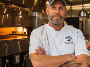 Chef Lance McWhorter standing in the kitchen at Heritage East at Culture ETX in Tyler, Texas, arms crossed in front of the wood-fired oven.