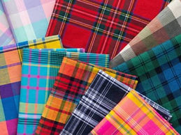 Multiple colorful Madras check fabric swatches in assorted plaid patterns spread out on a white surface, wholesale Madras check fabric India