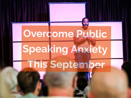 Man speaking on stage with "Overcome Public Speaking Anxiety This September" text. Audience in foreground, curtain backdrop.