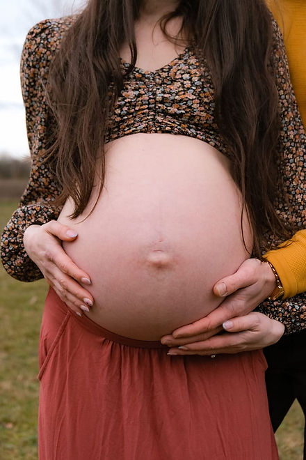 A professional maternity photoshoot by Frankie Smith, featuring an expectant mother and her birth partner gently cradling a pregnant belly for a local Warwickshire hypnobirthing and antenatal practice.