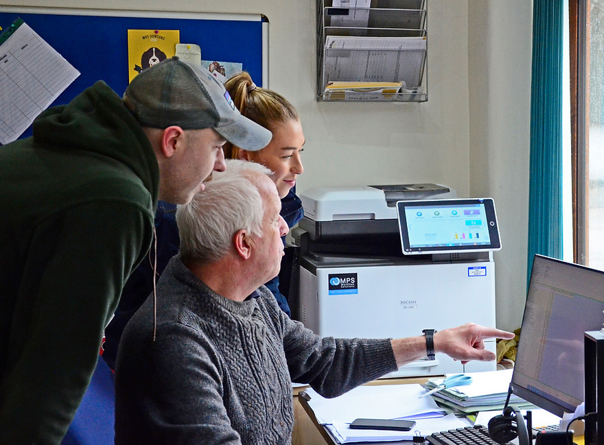 Farmers discussing data on their office computer.