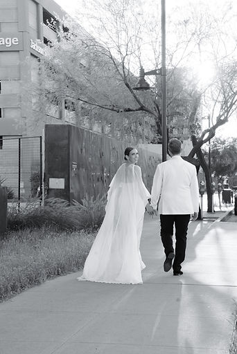 Bride & groom walking with bride looking back at camera.