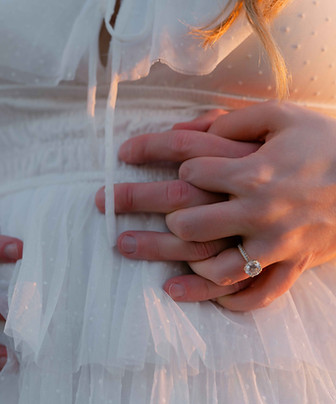 Couple holding hands for a classic engagement ring photo.