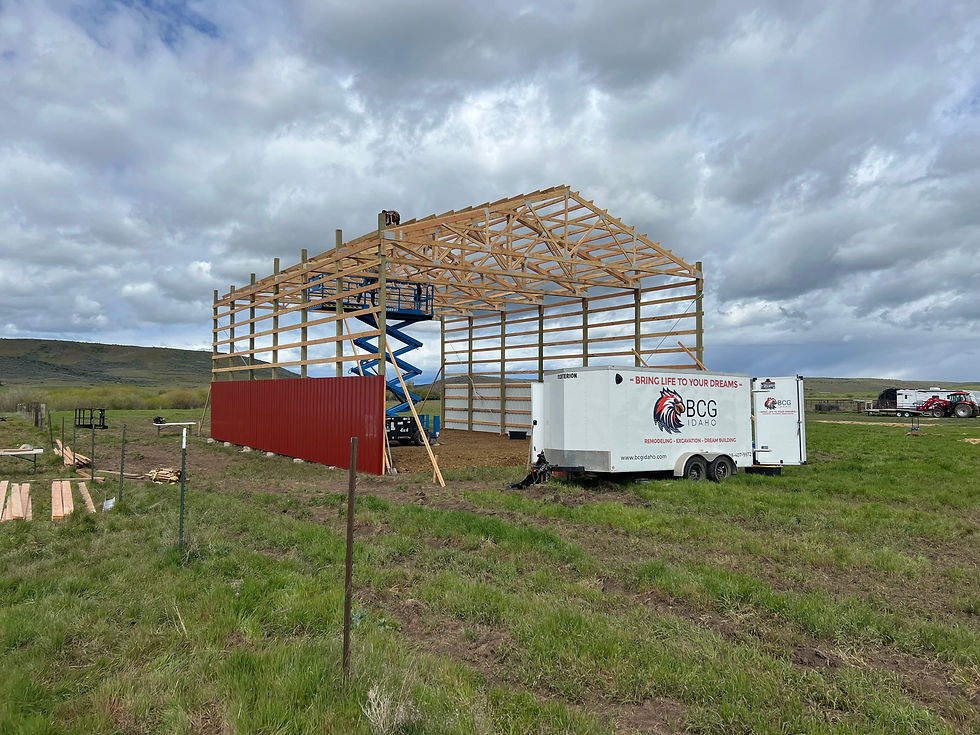 red pole barn being built with lumber and trusses and large lift in rural Idaho