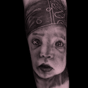 Niezwykle precyzyjny i realistyczny tatuaż portretowy przedstawiający twarz dziecka w stylu black and grey, wykonany w studio