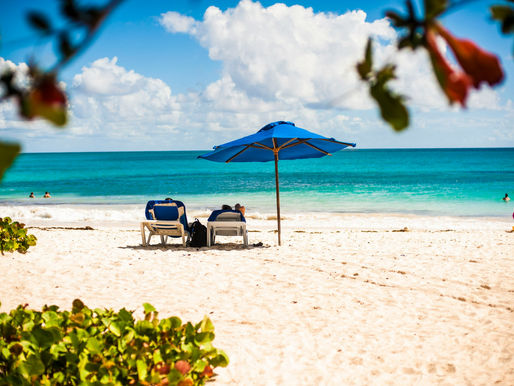 two beach chairs under an umbrella on the beach