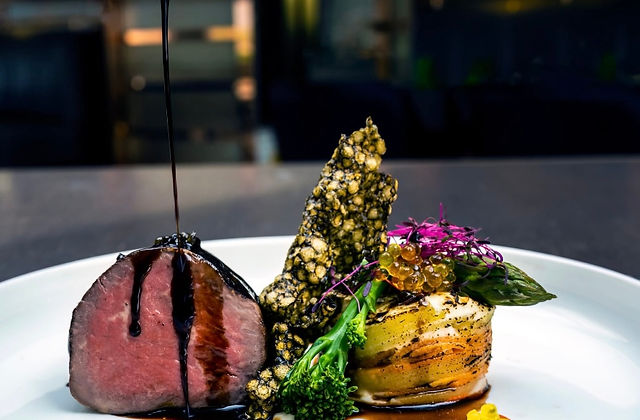 Pouring sauce over beef tenderloin with vegetables