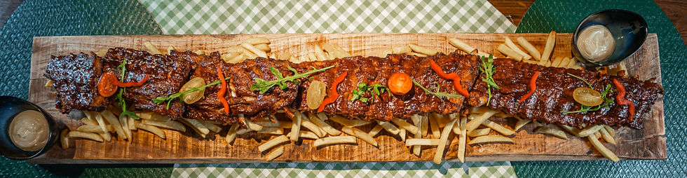 Meterplatte mit Ripperl und Pommes auf dem Tisch im Restaurant