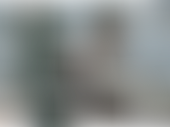 Mulher sentada de forma relaxada em uma poltrona, com os pés apoiados no braço, escrevendo em um caderno. Ela observa o que escreve com expressão reflexiva. Ao fundo, há uma janela com cortina, criando um clima calmo e introspectivo.