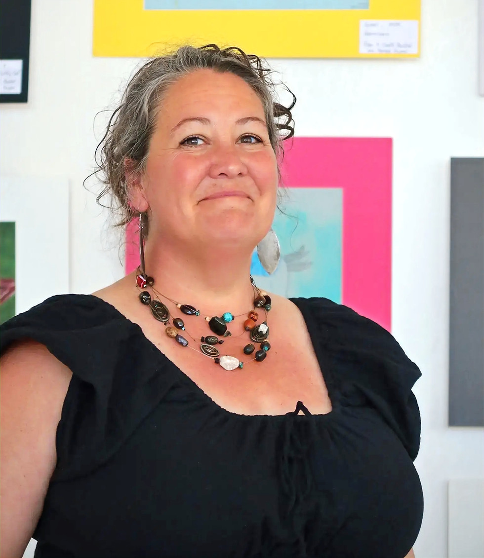 Woman smiling in front of artwork in a studio.