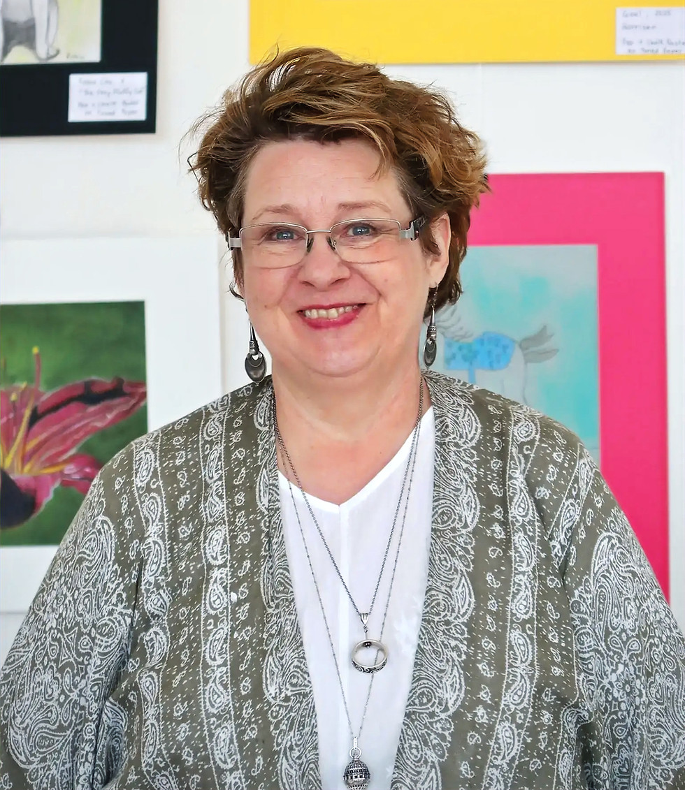 Smiling woman with glasses standing in an art studio.