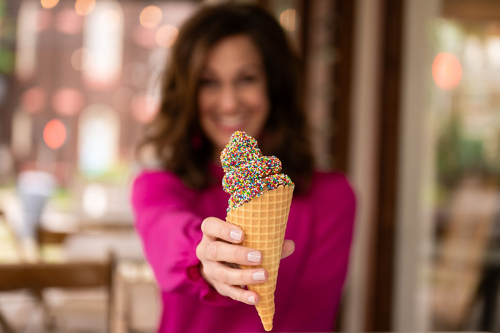 Woman in magenta holding a cone of ice cream with sprinkles 