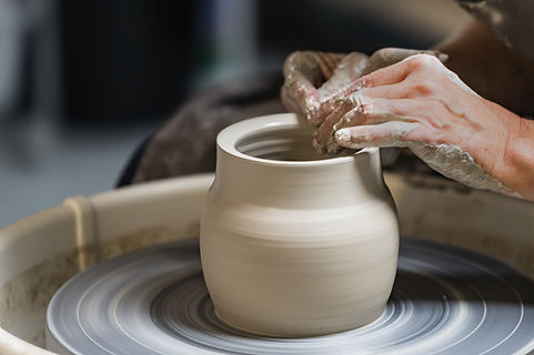 a white stoneware pot being thrown on the potters wheel