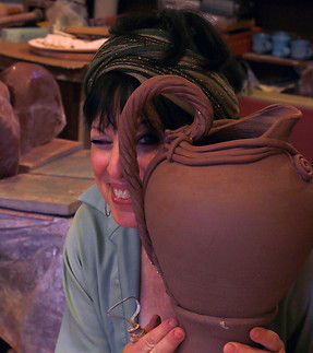 Head teacher and owner, Marilyn, peering through the handle of a large, wheel thrown and altered pitcher.