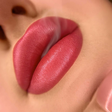 Macro beauty photography shot of a woman with plump pinkish red lipstick exhaling a thin stream of smoke from her lips. Premium cosmetic lip filler advertising campaign by Nello Johnson Photography Katrineholm Sweden, editorial beauty studio portrait.