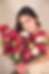 Mujer sonriente sosteniendo un gran ramo de flores rojas y blancas.