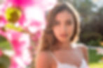 Mujer joven posando junto a flores rosas en La Biblioteca