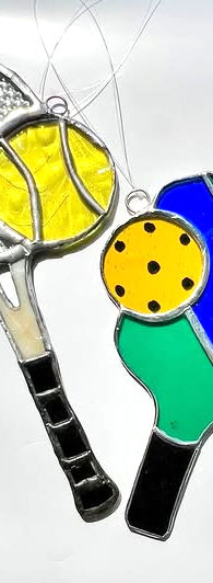A stained glass tennis racket and tennis ball, and a stained glass paddle racket and ball
