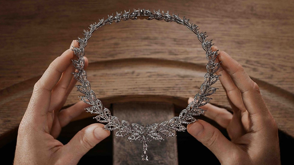 White-gold laurel wreath necklace held by hand before its coloured diamonds are set, showing the unfinished structure of a high jewellery piece.